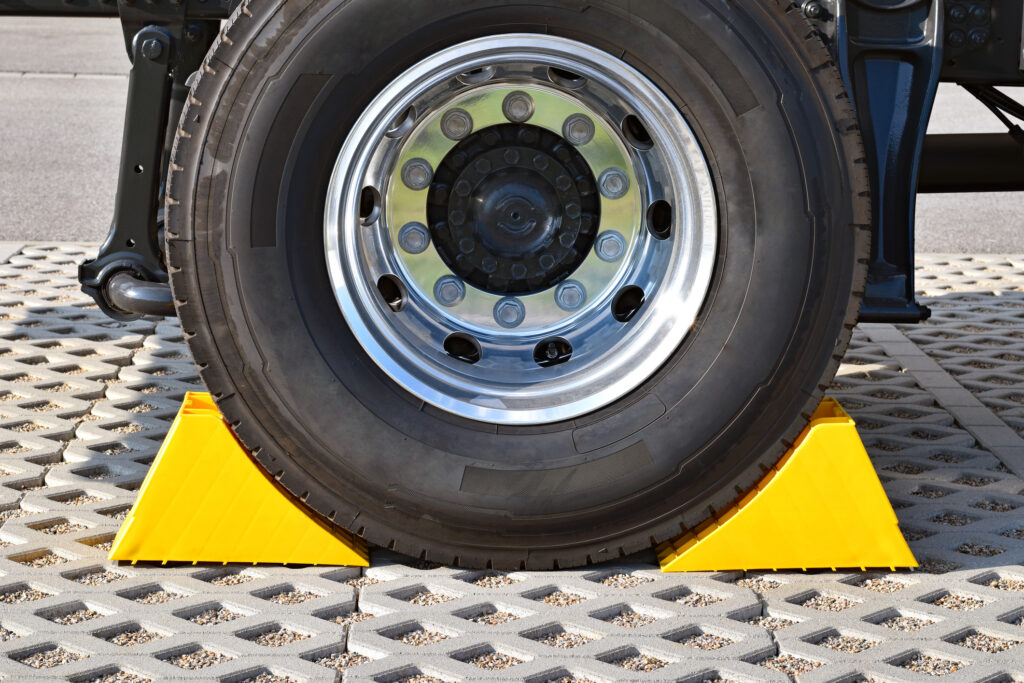 Two yellow chocks at the wheel of a parked truck.