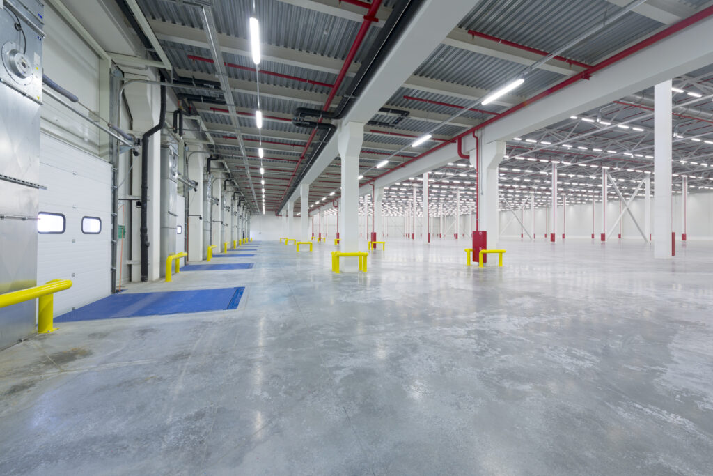 Inside view of an empty loading facility with rows of white lights on the roof. 