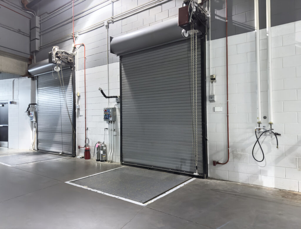 Indoor warehouse entrance showing two loading docks with closed shutter doors.